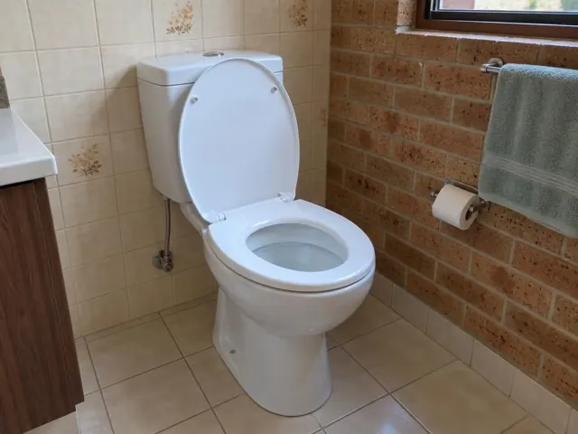 Clean white toilet in a tiled bathroom with brick feature wall in Heathcote